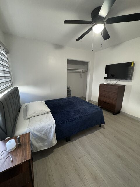 Private resident bedroom with navy bedding, dark wood furniture, and a closet