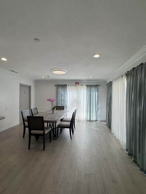 Dining room with a long table set for a meal, sheer curtains, and an orchid centerpiece