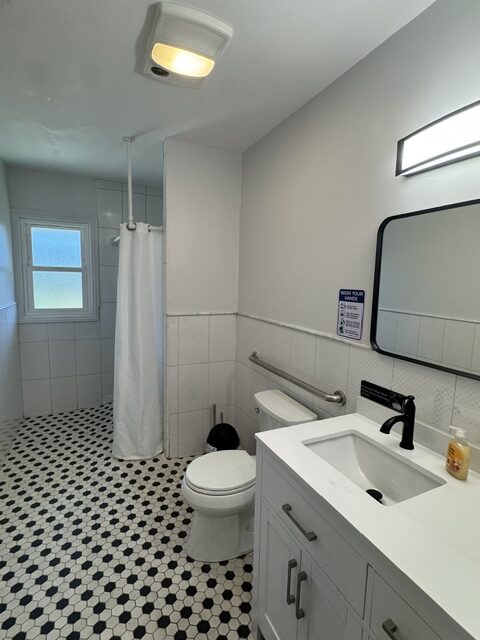 Bright bathroom with a shower, grab bars, and black-and-white tile